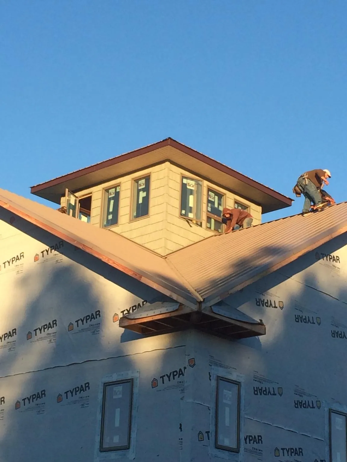 Roofers working around a rooftop cupola on a new metal roof at sunset — Roof Waterproofing in Lancaster by Roofing Brothers